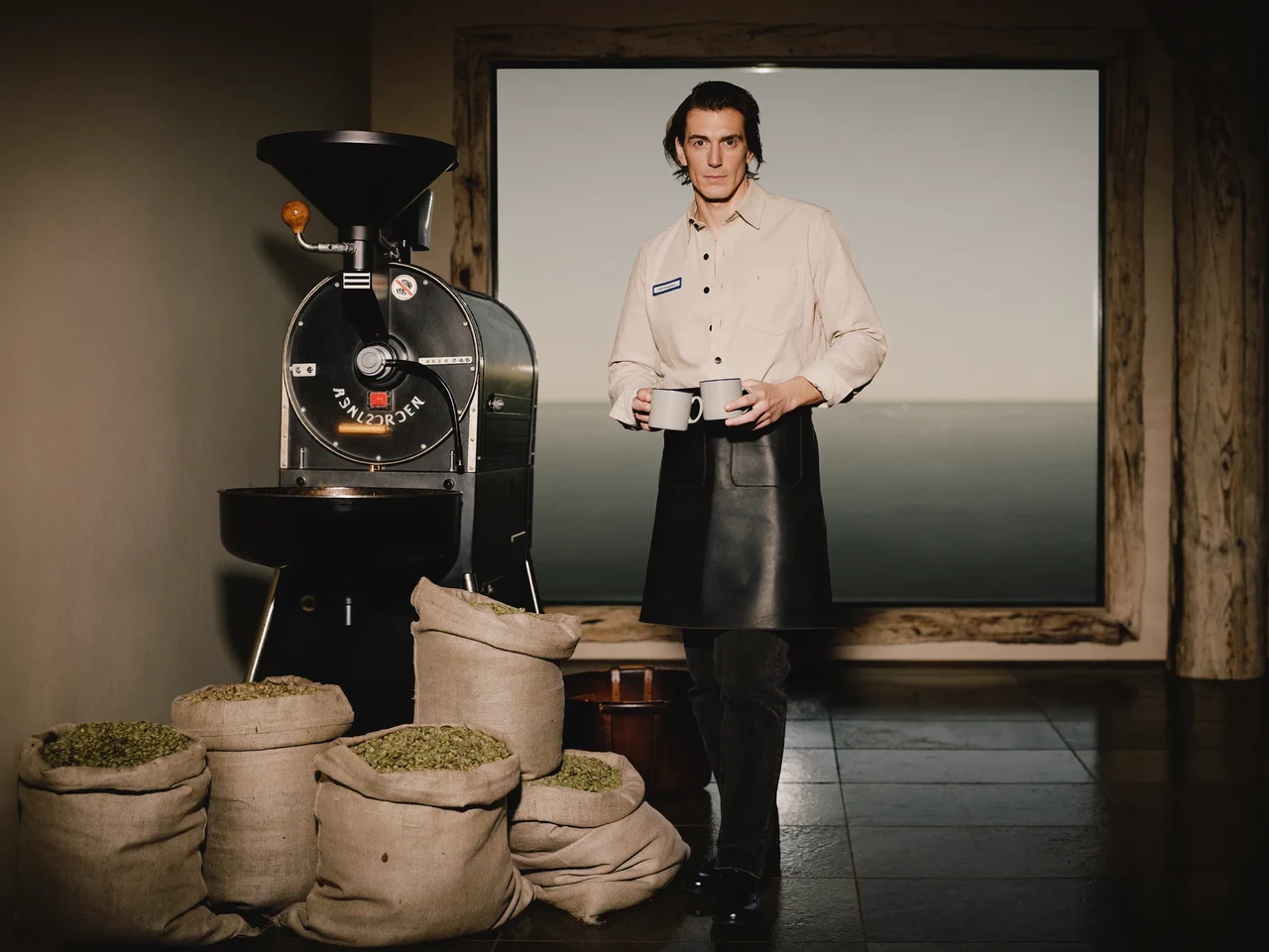 Kleine Küstenrösterei mit Trommelröster und Rohkaffeesäcken im hellen Morgenlicht der Ostsee